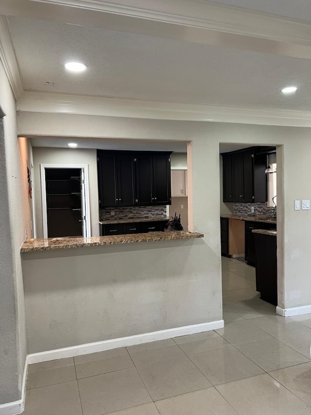 1506 Grand Valley Dr, Houston, TX 77090 - kitchen with dark cabinetry, ornamental molding, decorative backsplash, baseboards, and light stone countertops