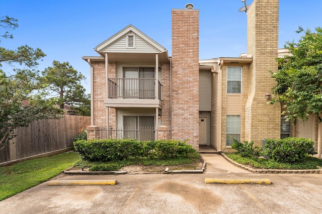 3100 Jeanetta St Unit 606, Houston, TX 77063 - view of front of home featuring a balcony, brick siding, a chimney, fence, and uncovered parking
