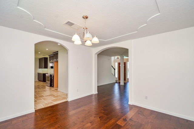 13523 Spring Ct, Tomball, TX 77375 - spare room with arched walkways, wood finished floors, baseboards, a chandelier, and a textured ceiling