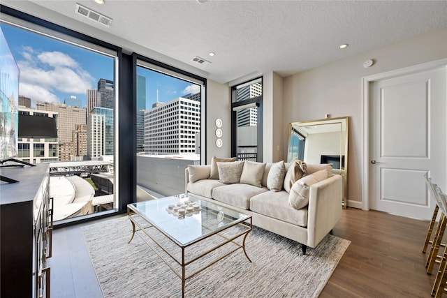 1211 Caroline St Unit 908, Houston, TX 77002 - living area featuring a textured ceiling, wood finished floors, a wall of windows, and recessed lighting