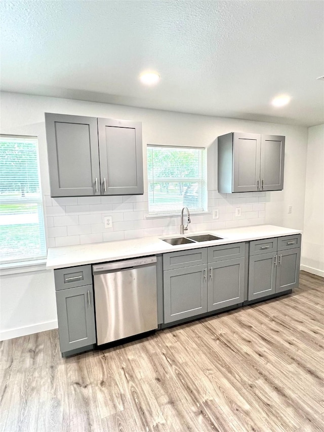 803 Hackberry St, Stafford, TX 77477 - kitchen with stainless steel dishwasher, gray cabinetry, a sink, light wood-style floors, and tasteful backsplash