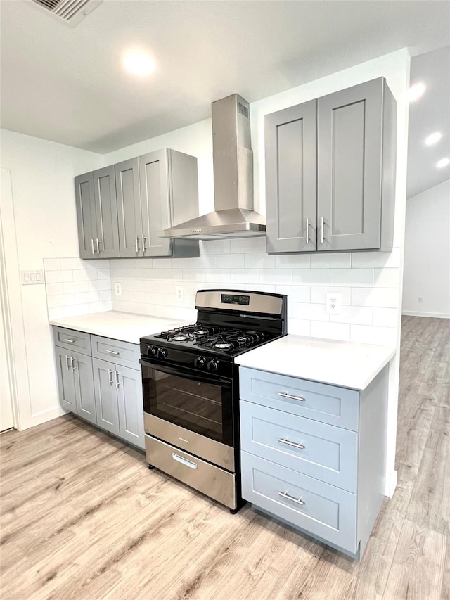 803 Hackberry St, Stafford, TX 77477 - kitchen featuring gas range, wall chimney range hood, gray cabinetry, light wood-type flooring, and light countertops