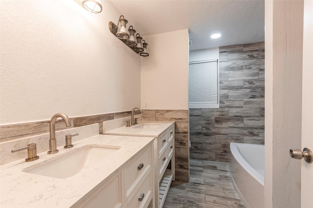 1535 Scott St, La Marque, TX 77568 - bathroom with tile walls, double vanity, a bath, recessed lighting, and a wainscoted wall