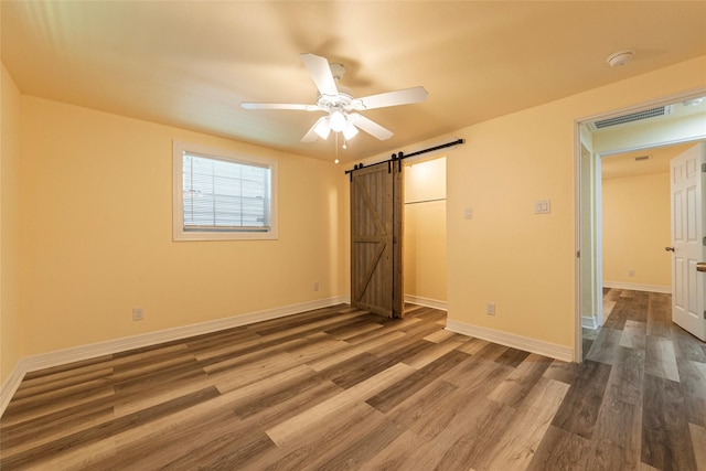 1535 Scott St, La Marque, TX 77568 - unfurnished bedroom featuring a barn door, wood finished floors, and baseboards