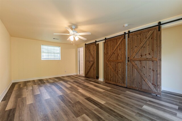 1535 Scott St, La Marque, TX 77568 - unfurnished bedroom featuring a barn door, dark wood finished floors, baseboards, and ceiling fan