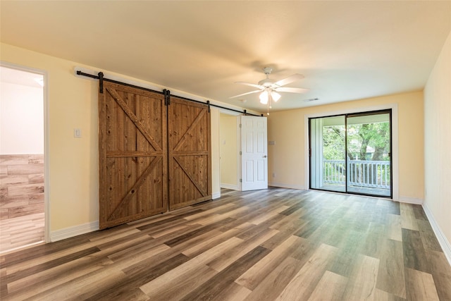 1535 Scott St, La Marque, TX 77568 - unfurnished room featuring a barn door, a ceiling fan, wood finished floors, and baseboards