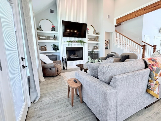 55 Ruskin Dr W, Montgomery, TX 77356 - living room featuring light wood-style floors, built in features, stairway, a fireplace, and high vaulted ceiling