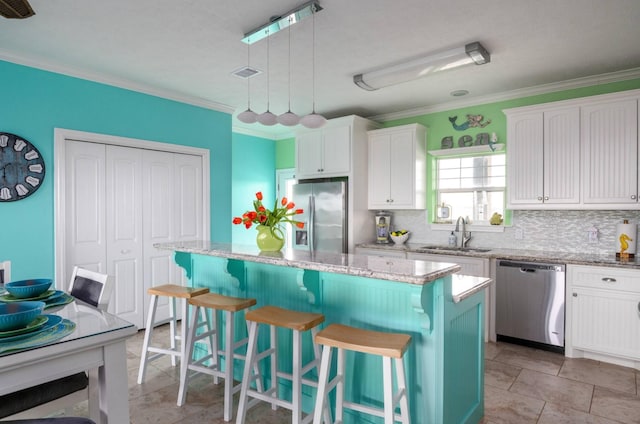 1109 Pompano Dr, Crystal Beach, TX 77650 - kitchen with stainless steel appliances, a sink, white cabinetry, a center island, and ornamental molding