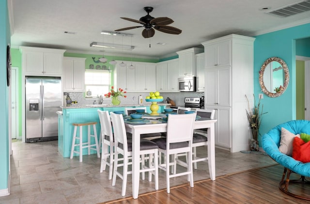 1109 Pompano Dr, Crystal Beach, TX 77650 - kitchen with appliances with stainless steel finishes, crown molding, a breakfast bar, tasteful backsplash, and ceiling fan