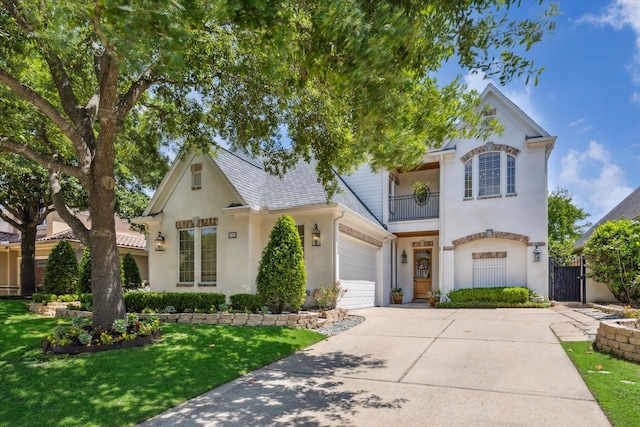 view of front of home featuring a balcony, concrete driveway, stucco siding, a gate, and a front lawn