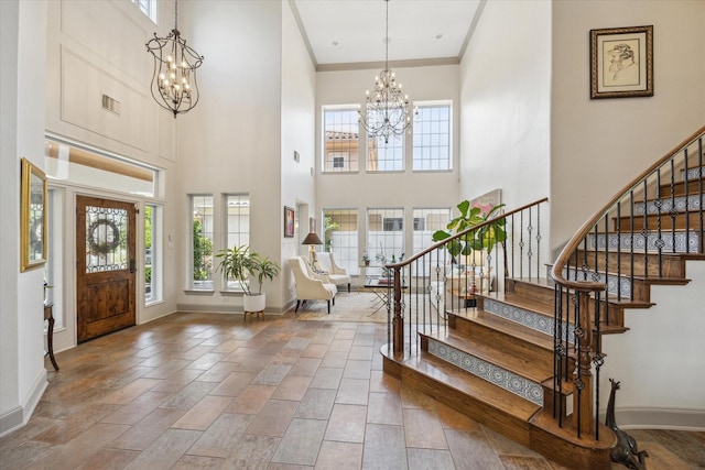 foyer entrance with a chandelier, healthy amount of natural light, a high ceiling, and crown molding