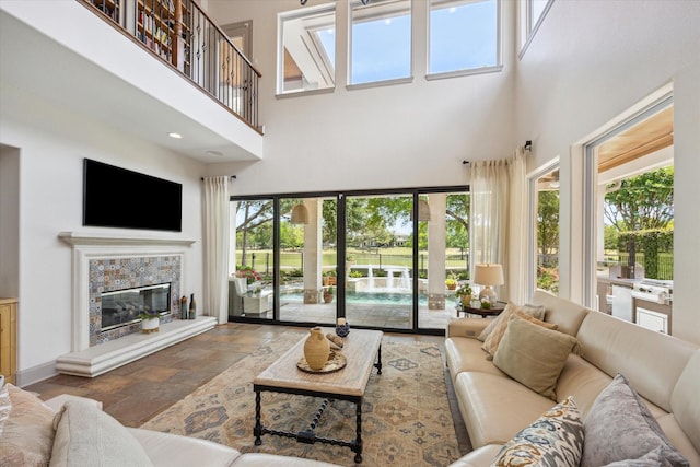 living room with a high ceiling, stone tile floors, a fireplace, and baseboards