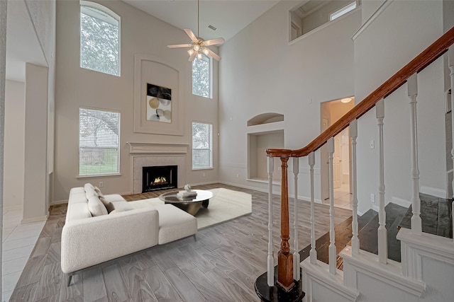 10210 Squirehill Ct, Houston, TX 77070 - living room featuring a towering ceiling, stairs, ceiling fan, a fireplace, and baseboards