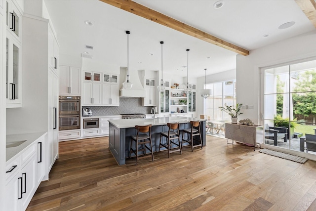 2224 N Blvd, Houston, TX 77098 - kitchen featuring custom range hood, appliances with stainless steel finishes, beam ceiling, wood finished floors, and white cabinets