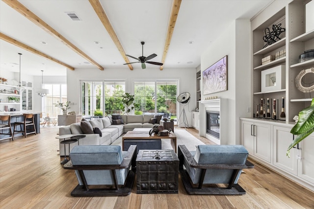 2224 N Blvd, Houston, TX 77098 - living area with a glass covered fireplace, ceiling fan, beam ceiling, and light wood finished floors