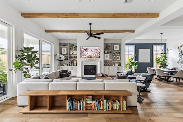 2224 N Blvd, Houston, TX 77098 - living room with a ceiling fan, beamed ceiling, wood finished floors, a glass covered fireplace, and a chandelier