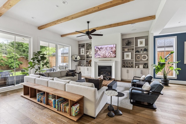 2224 N Blvd, Houston, TX 77098 - living area featuring wood-type flooring, a glass covered fireplace, beamed ceiling, ceiling fan, and built in shelves