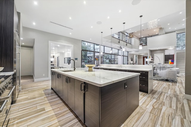 4002 Chatham Ln, Houston, TX 77027 - kitchen featuring a spacious island, modern cabinets, a sink, dark brown cabinetry, and double oven range