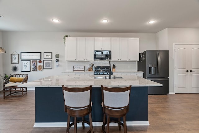13110 Mid Stocket Dr, Humble, TX 77346 - kitchen featuring black microwave, stainless steel refrigerator with ice dispenser, an island with sink, a sink, and range