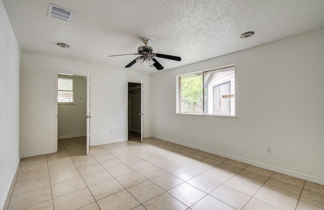 2614 Lemonwood Ln, Houston, TX 77038 - unfurnished bedroom featuring a textured ceiling, a closet, a ceiling fan, baseboards, and light tile patterned flooring