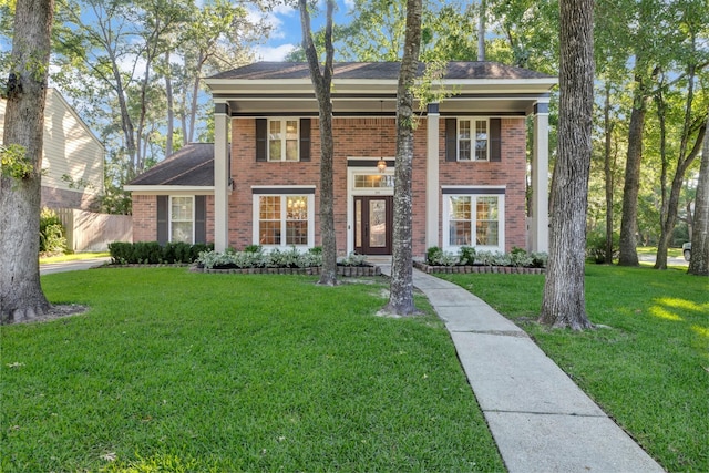 greek revival inspired property featuring brick siding and a front yard