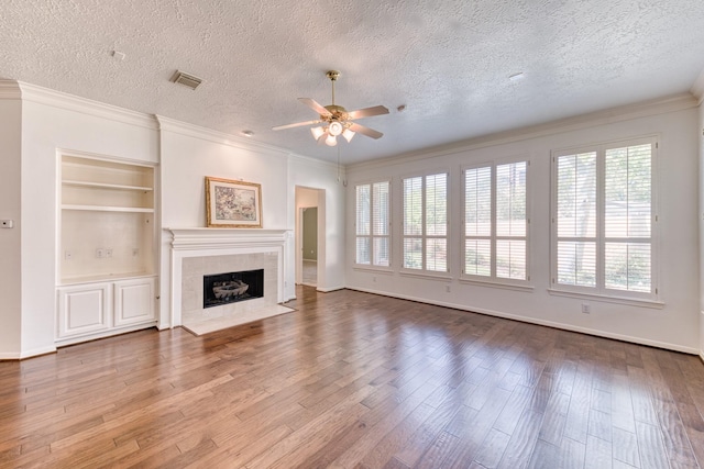 1114 Ridgeburg Ct, Houston, TX 77077 - unfurnished living room featuring a ceiling fan, a textured ceiling, a tile fireplace, wood finished floors, and built in features