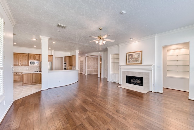 1114 Ridgeburg Ct, Houston, TX 77077 - unfurnished living room with a ceiling fan, hardwood / wood-style floors, ornate columns, crown molding, and a fireplace