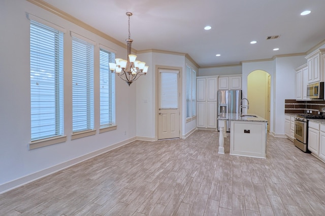 1184 Nelson Falls Ln, Houston, TX 77008 - kitchen featuring appliances with stainless steel finishes, a chandelier, light wood-style flooring, arched walkways, and crown molding