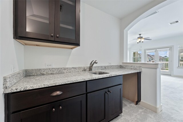 1184 Nelson Falls Ln, Houston, TX 77008 - kitchen featuring a sink, light colored carpet, glass insert cabinets, a ceiling fan, and light stone counters