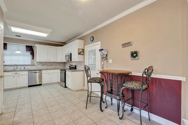 9822 El Chaco St, Baytown, TX 77521 - kitchen featuring stainless steel appliances, ornamental molding, a sink, decorative backsplash, and white cabinets