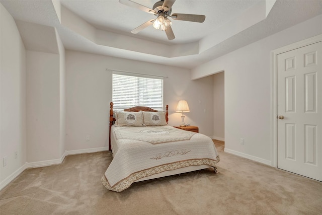 9822 El Chaco St, Baytown, TX 77521 - bedroom featuring light colored carpet, a tray ceiling, baseboards, and a ceiling fan