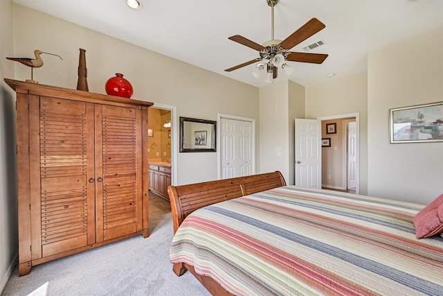 bedroom featuring light colored carpet, connected bathroom, and a ceiling fan