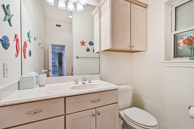 half bath with toilet, vanity, and a chandelier