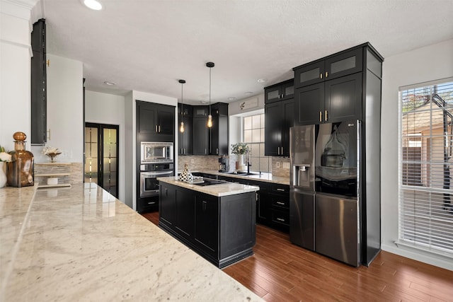 14902 Autumnvale Ln, Cypress, TX 77429 - kitchen featuring stainless steel appliances, dark cabinetry, decorative backsplash, light stone countertops, and recessed lighting