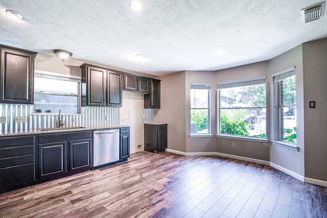 10835 Spruce Dr S, La Porte, TX 77571 - kitchen featuring dishwasher, a sink, light wood-type flooring, baseboards, and a textured ceiling