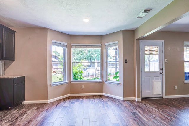 10835 Spruce Dr S, La Porte, TX 77571 - unfurnished dining area featuring dark wood finished floors, baseboards, healthy amount of natural light, and a textured ceiling