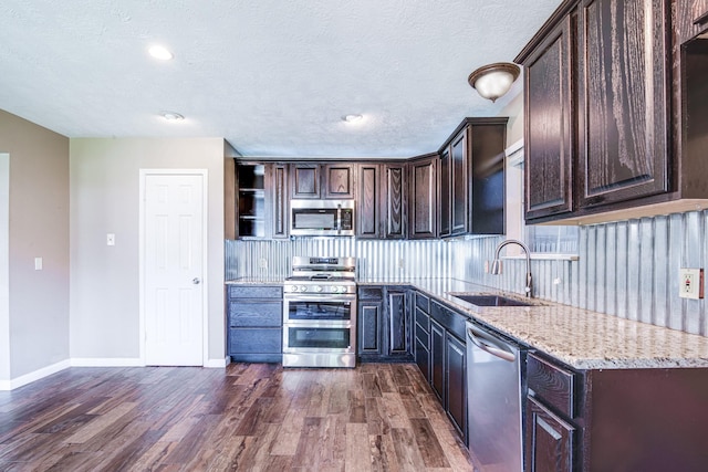 10835 Spruce Dr S, La Porte, TX 77571 - kitchen featuring stainless steel appliances, a sink, dark brown cabinets, dark wood-style floors, and tasteful backsplash