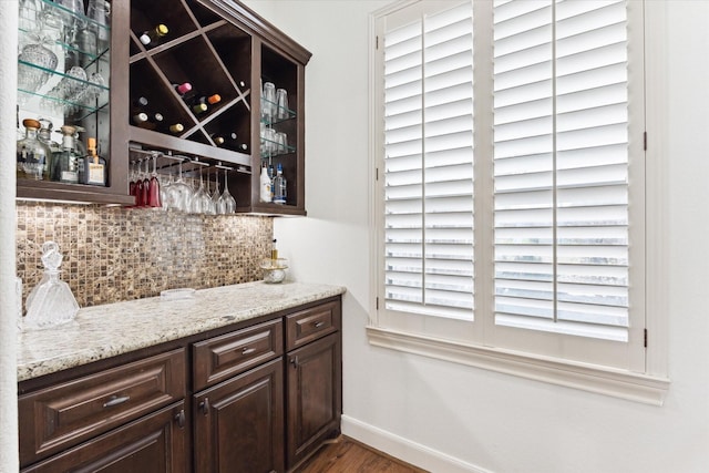 indoor dry bar featuring baseboards, decorative backsplash, and wood finished floors