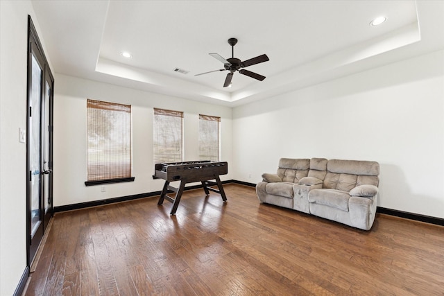 recreation room featuring a tray ceiling, dark wood-style flooring, baseboards, ceiling fan, and recessed lighting