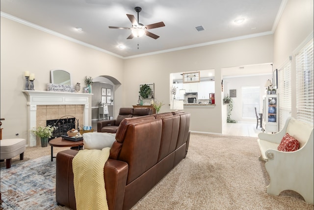 12127 Via San Rocco Ct, Cypress, TX 77429 - living area with light colored carpet, ceiling fan, crown molding, a tile fireplace, and arched walkways