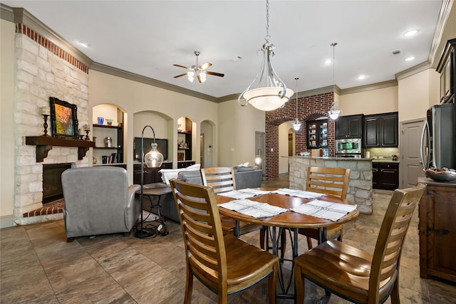 9010 Kapri Ln, Houston, TX 77025 - dining area with arched walkways, crown molding, a ceiling fan, a stone fireplace, and recessed lighting