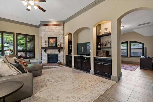 9010 Kapri Ln, Houston, TX 77025 - tiled living room with a ceiling fan, ornamental molding, a stone fireplace, and built in features