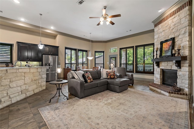 9010 Kapri Ln, Houston, TX 77025 - living room with crown molding, ceiling fan, a stone fireplace, recessed lighting, and dark stone finish floors