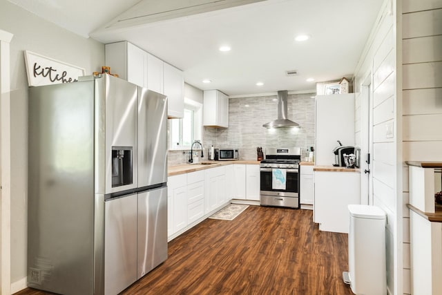 2735 County Road 208, Danbury, TX 77534 - kitchen with stainless steel appliances, wall chimney range hood, butcher block countertops, a sink, and backsplash