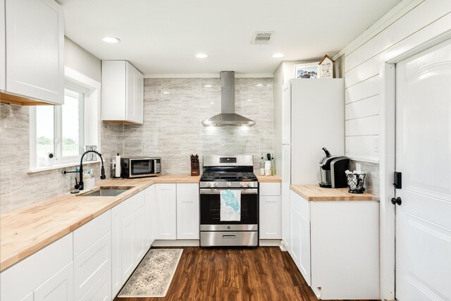 2735 County Road 208, Danbury, TX 77534 - kitchen with appliances with stainless steel finishes, butcher block counters, wall chimney exhaust hood, a sink, and decorative backsplash