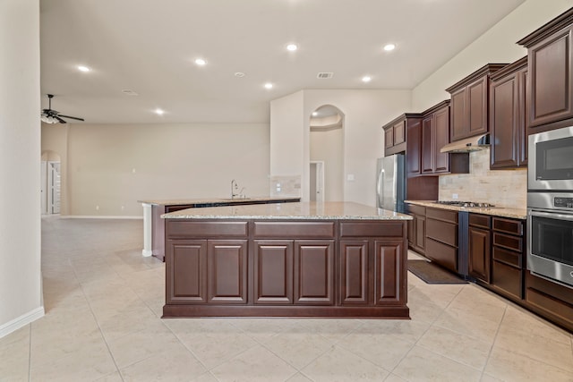 28010 Drifters Bend Dr, Spring, TX 77386 - kitchen featuring appliances with stainless steel finishes, arched walkways, a sink, a kitchen island, and decorative backsplash