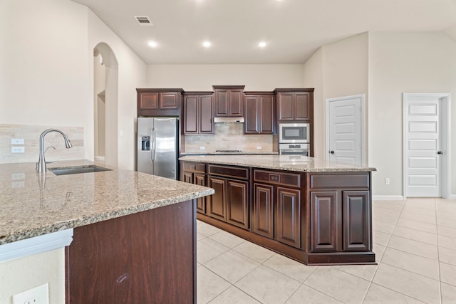 28010 Drifters Bend Dr, Spring, TX 77386 - kitchen featuring stainless steel appliances, a sink, decorative backsplash, dark brown cabinetry, and light tile patterned floors