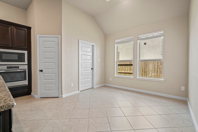 28010 Drifters Bend Dr, Spring, TX 77386 - kitchen featuring oven, built in microwave, vaulted ceiling, light stone countertops, and dark brown cabinets
