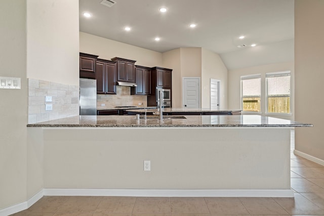 28010 Drifters Bend Dr, Spring, TX 77386 - kitchen with stainless steel appliances, dark brown cabinets, light stone counters, tasteful backsplash, and vaulted ceiling