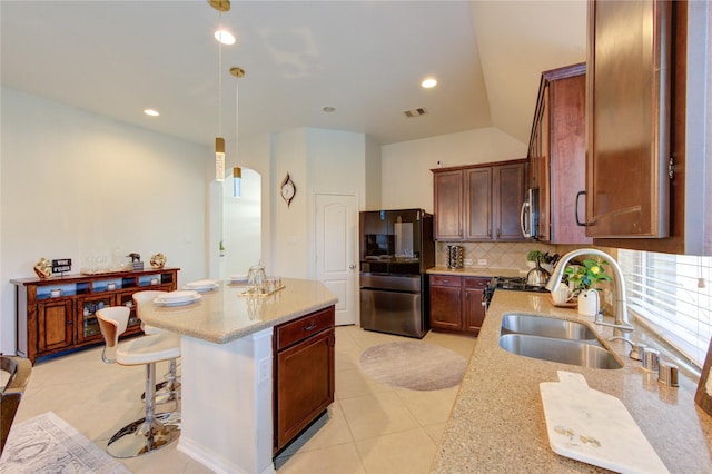 19503 Sundance Edge Ct, Richmond, TX 77407 - kitchen featuring freestanding refrigerator, a sink, tasteful backsplash, a center island, and light tile patterned floors